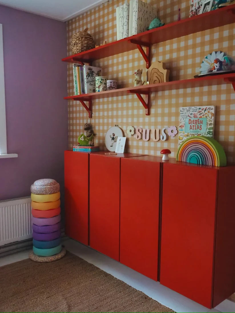 Ockergelbe Gingham-Tapete von Atelier Chien hinter einem roten Schrank und Wandregalen.
