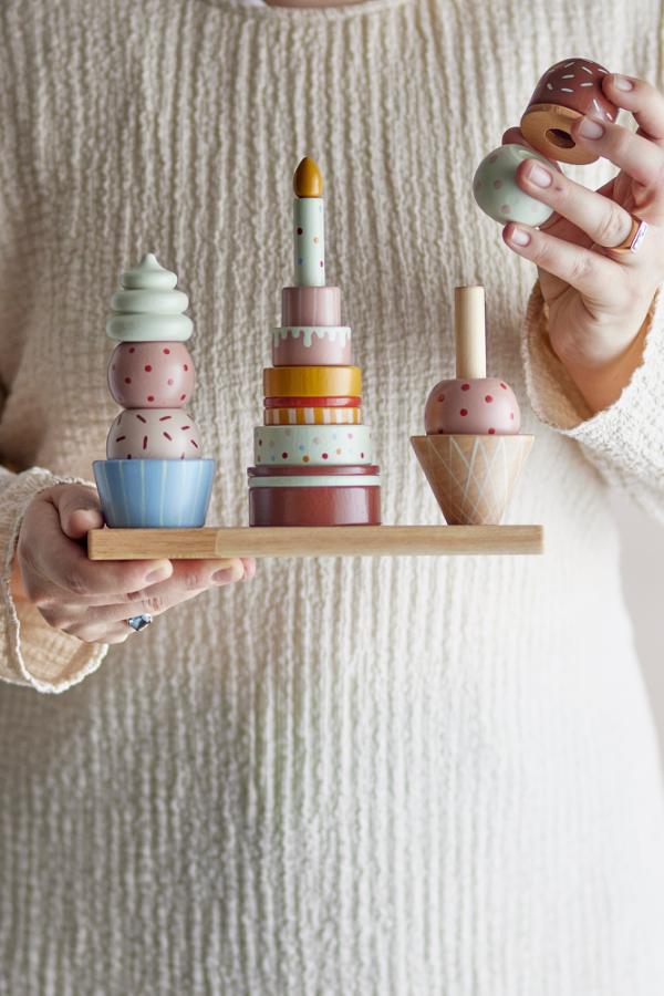 Celebrate Activity Toy – Bloomingville MINI : détail d'une main posant une pièce sur la tour à empiler.
