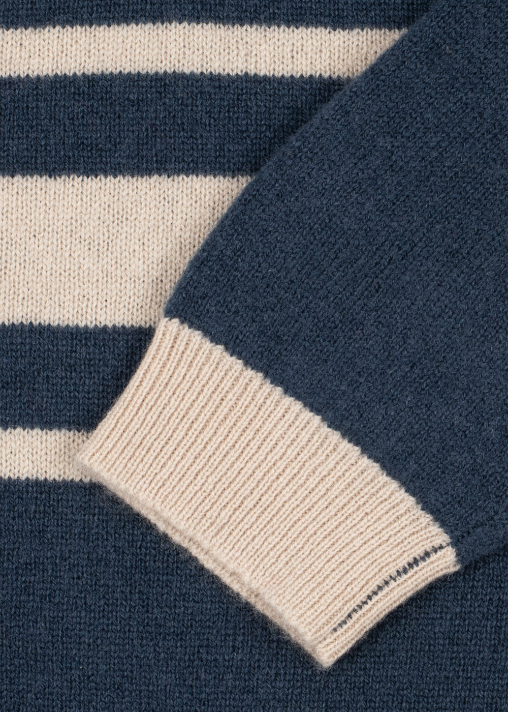Polo en laine Basi – Dark Blue Stripe – Konges Sløjd : détail des rayures claires et du bord de manche du polo bleu.