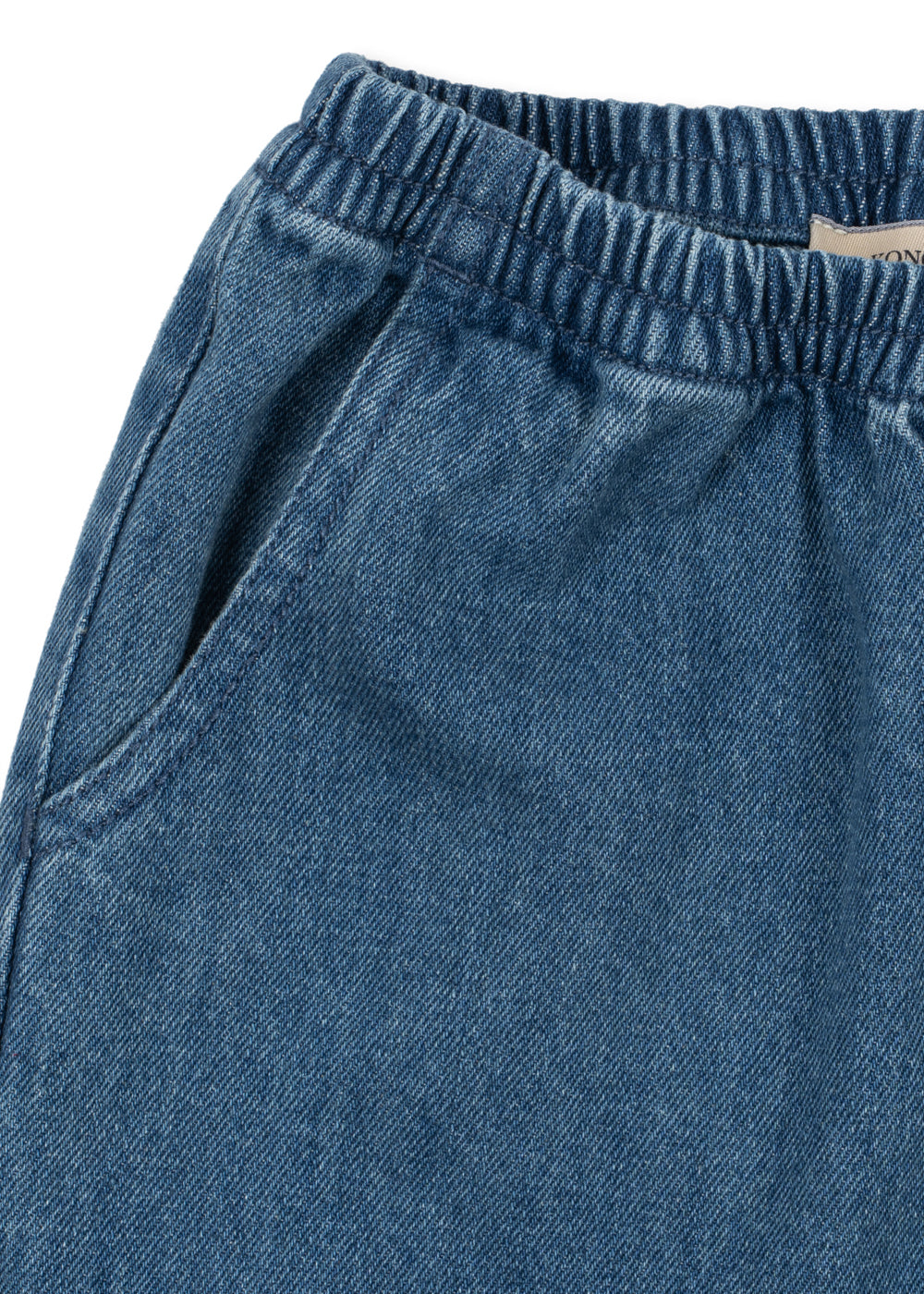 Denimhose Magot – Denim Blue – Konges Sløjd: Detail des elastischen Bunds und der Eingrifftasche der Denimhose.